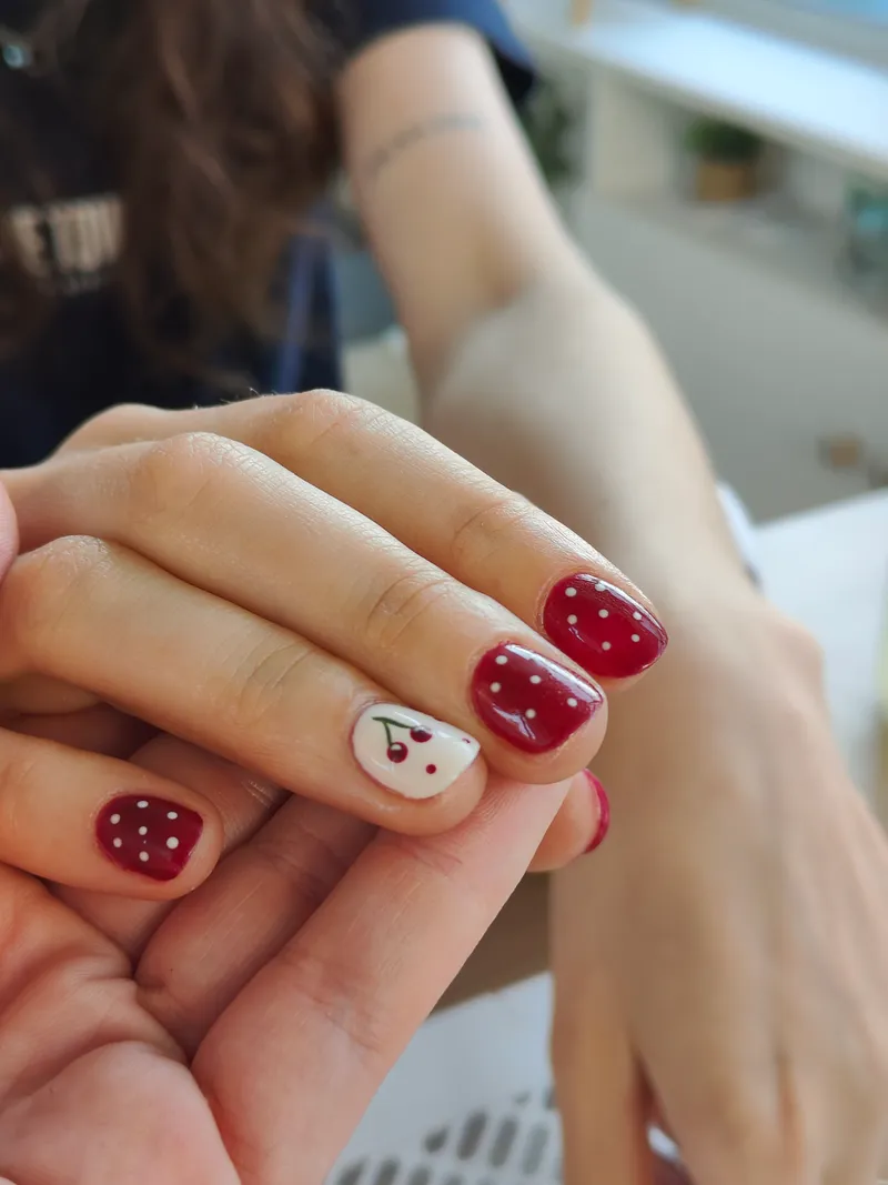 Manucure rouge à pois blancs et nail art cerise réalisée par Maison M pour Lucie